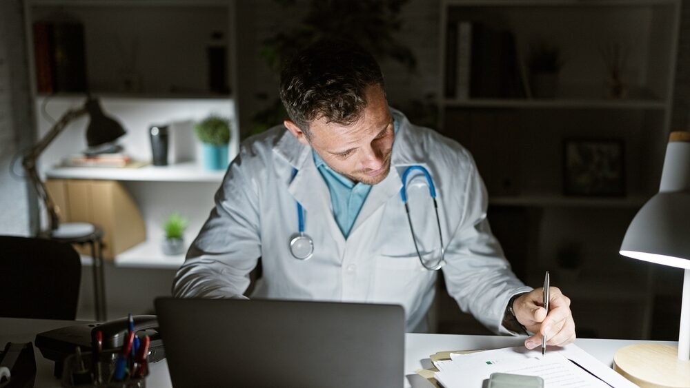 Handsome,Hispanic,Man,In,Medical,Uniform,With,Stethoscope,Taking,Notes