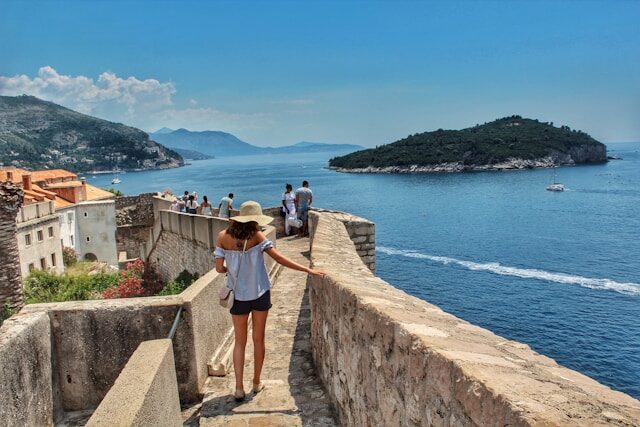 Frau geht auf einer Steintreppe in Kroatien zum Meer hinunter